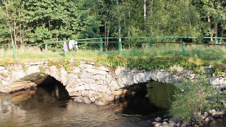 Vandrare på äldre stenbro över vattendrag