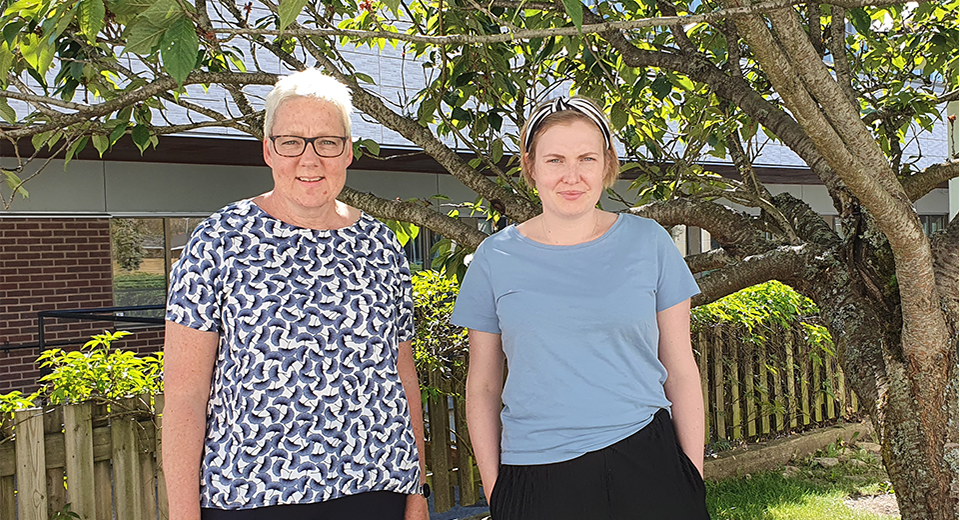 Två medarbetare från utredningsenheten, Kristina och Jennifer. Står utomhus intill ett träd i vårs