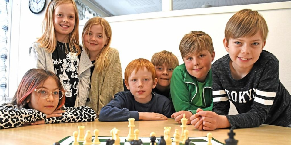 7 elever bakom ett bord med ett schack spel på