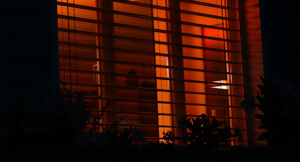 Bild på ett fönster på ett hus med rött sken lysande ut