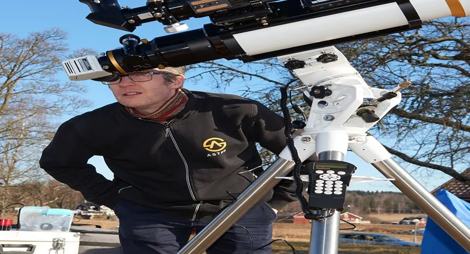 Gunnar Sporrong står lutad framåt och tittar in i ett teleskop.