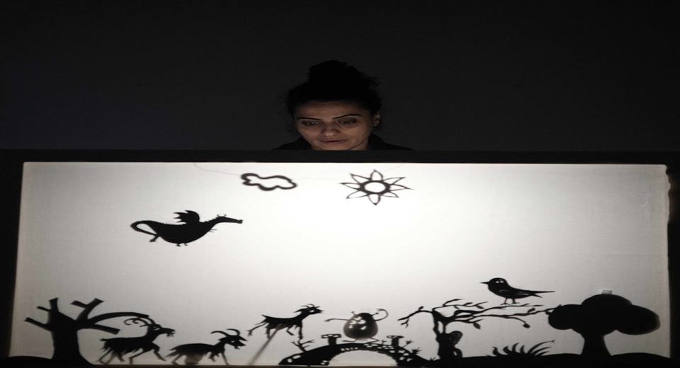 Helen Al Janabi står bakom en vit skärm med svarta figurer på.