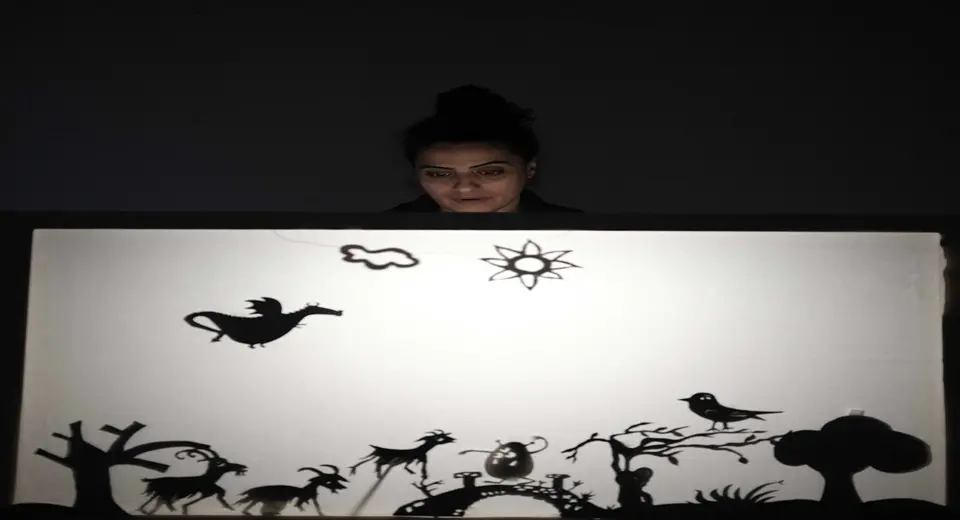 Helen Al Janabi står bakom en vit skärm med svarta figurer på.