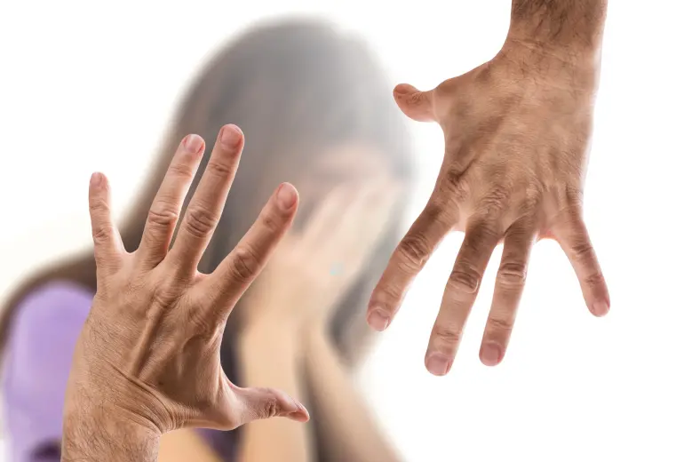 Två händer i förgrunden som rör sig hotfullt mott suddig kvinna i bakgrunden som håller händerna framför sitt ansikte