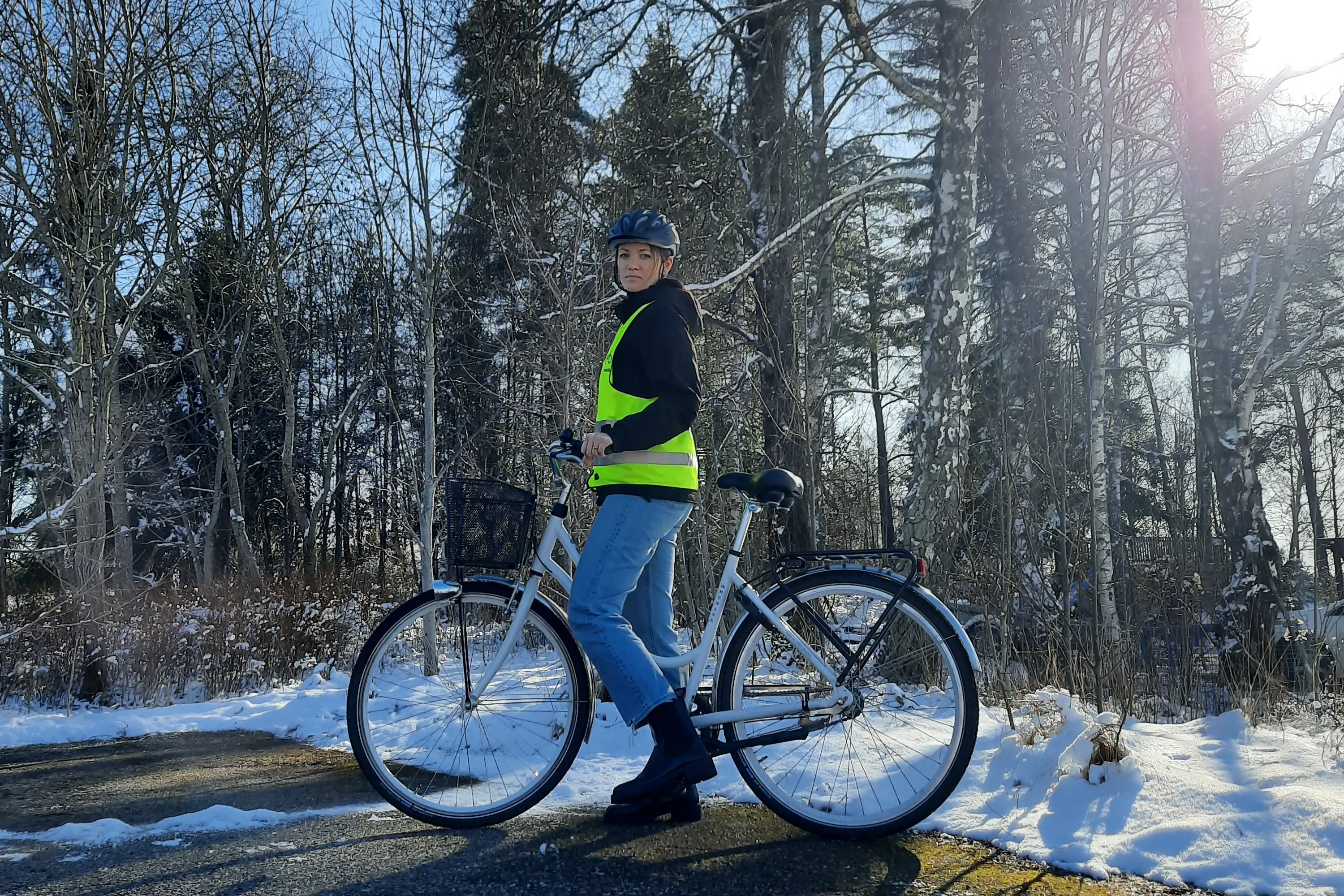 Person med cykel på vinterväg och solsken