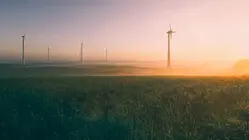 Vindkraftverk på fält i soluppgång